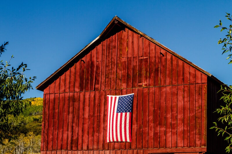 blog-us-flag-on-barn - AC Flag & Banner Nylon vs Polyester Flags: Which Material Lasts Longer and Fits Your Needs? - AC Flag & Banner